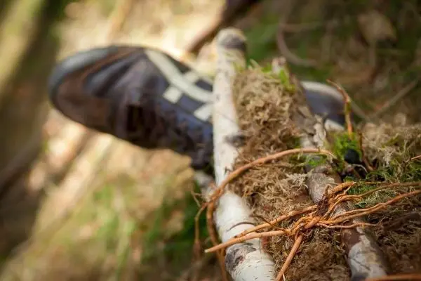 Selbstgebaute Konstruktion aus Ästen und Moos mit einem Schuh im Hintergrund