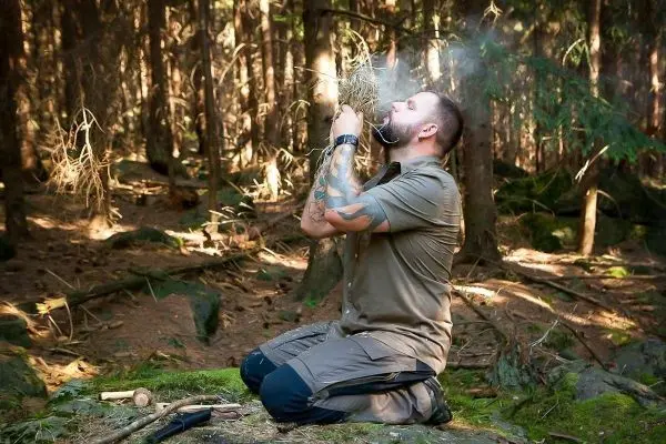 Zunder glimmt in den Händen, Rauch steigt auf