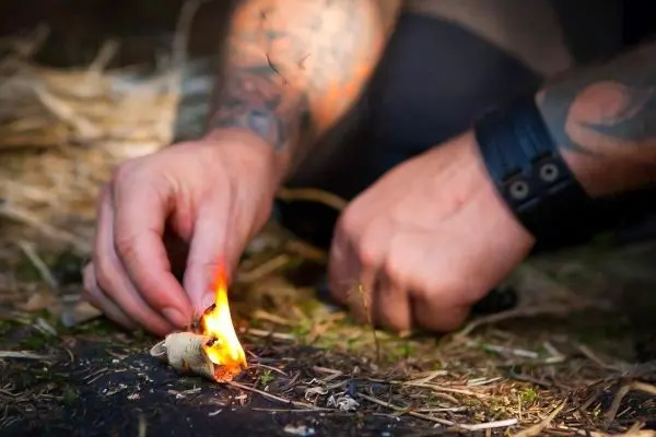 Zunder glimmt in der Hand, während eine kleine Flamme entsteht