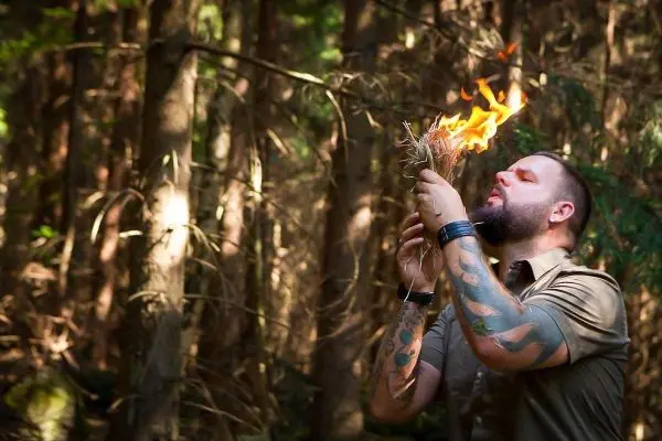 Zunder glimmt in der Hand, während eine kleine Flamme entsteht