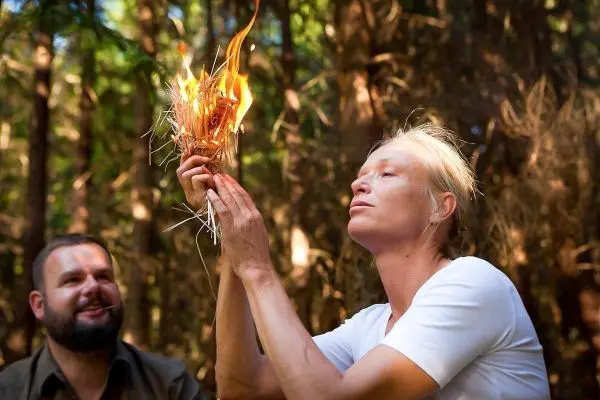 Zunder glimmt in der Hand, während eine Person ihn anbläst