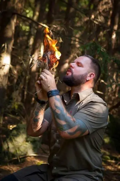 Zunder glimmt in der Hand, während Feuer entfacht wird