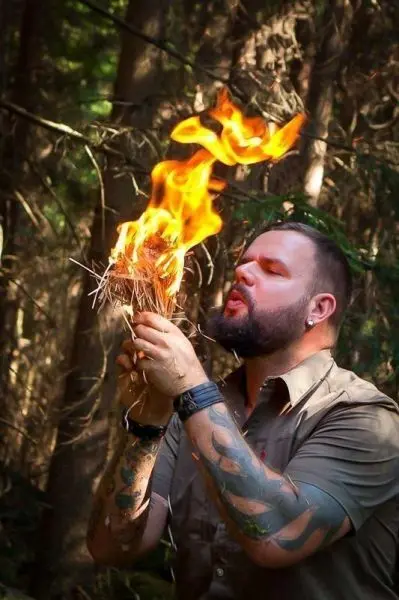 Zunder glimmt in Händen, kleine Flamme entfacht