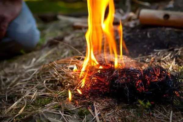 Zunder glimmt und kleine Flamme entsteht auf dem Boden