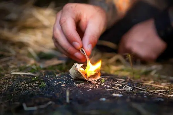 Zunder glimmt, während eine Hand ihn entzündet