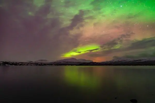 Farbenfrohe Nordlichter spiegeln sich im ruhigen Wasser eines Sees