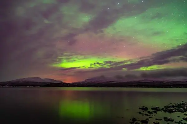 Farbenfrohes Nordlicht spiegelt sich im ruhigen Wasser eines Sees