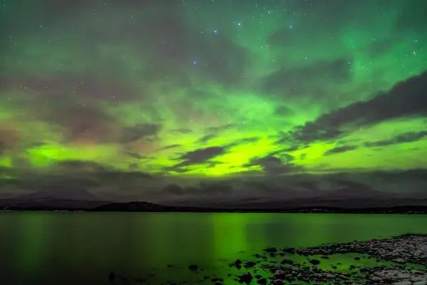 Grüne Lichtreflexionen auf der Wasseroberfläche unter bewölktem Himmel