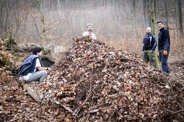 Gruppe arbeitet an einem großen Haufen aus Laub und Ästen im Wald