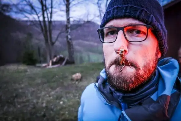 Mann mit Brille trägt einen Käfer an der Nase im Freien