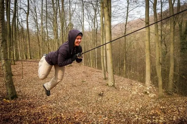 Person schwingt an einem Seil zwischen Bäumen