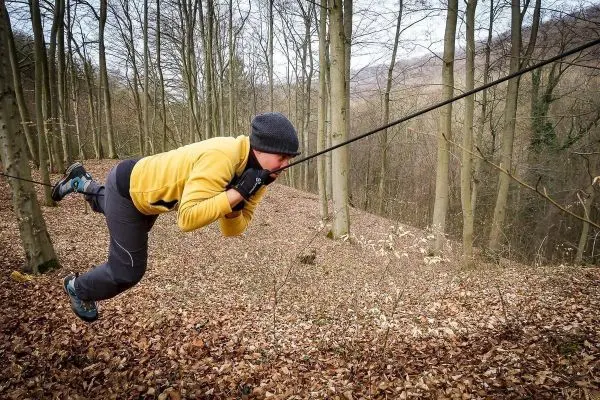 Person zieht sich an einem Seil durch den Wald beim Überlebenstraining