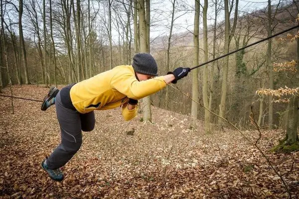 Überquert eine selbstgebaute Seilbrücke im Wald