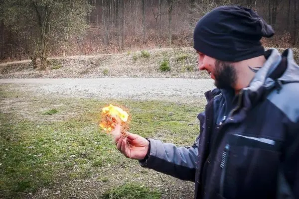 Zunder glimmt in der Hand, kleine Flamme sichtbar