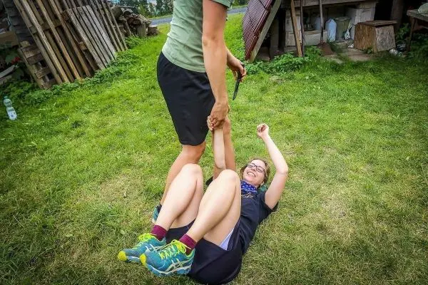 Eine Person zieht eine andere Person am Arm vom Boden hoch