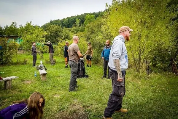 Gruppe von Personen in einem grünen Gelände, einige tragen Rucksäcke und Ausrüstung