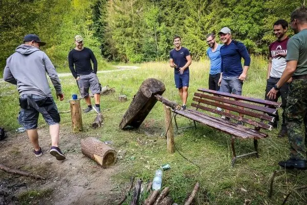 Gruppe von Personen steht um eine selbstgebaute Bank im Freien