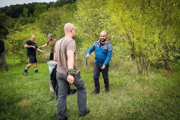 Gruppenteilnehmer üben eine Seilquerung in der Natur mit einem improvisierten Seil