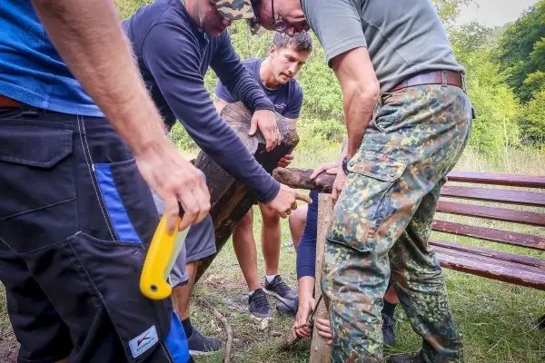 Gruppierung hebt einen schweren Holzstamm für eine Konstruktion an
