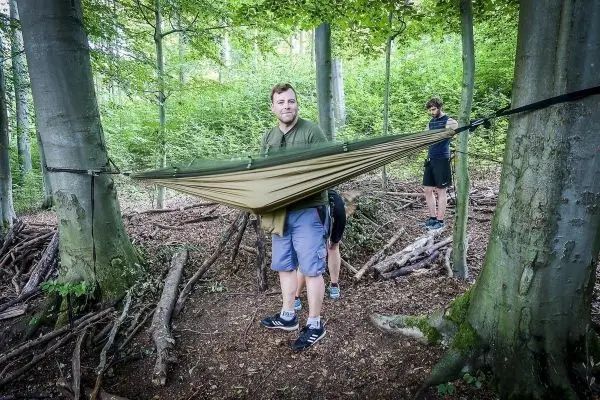 Hängematte wird zwischen zwei Bäumen gespannt, während eine Person sie hält