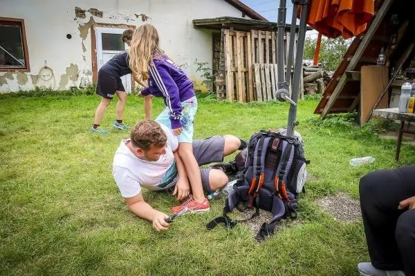 Junge liegt auf dem Boden, Mädchen steht auf seinen Schultern, Rucksack daneben