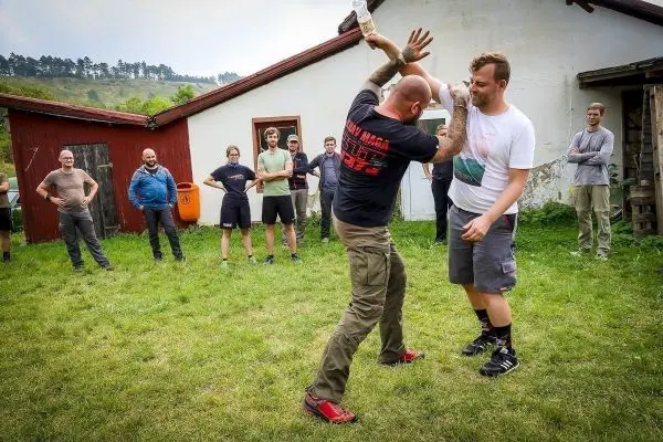Kampftraining mit zwei Teilnehmern in einer Wiese vor einem Gebäude