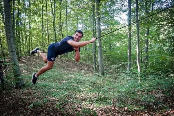Mann überquert selbstgebaute Seilbrücke im Wald