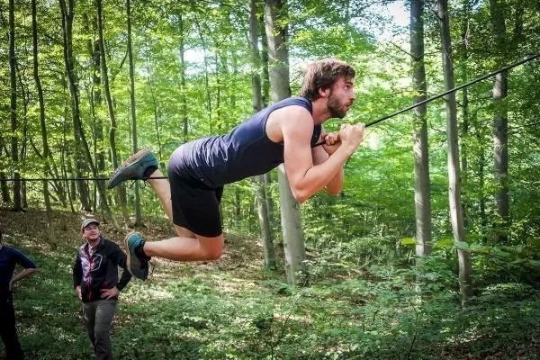 Mann überquert selbstgebaute Seilbrücke im Wald