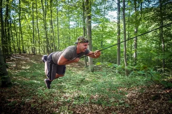 Mann überquert selbstgebaute Seilbrücke im Wald