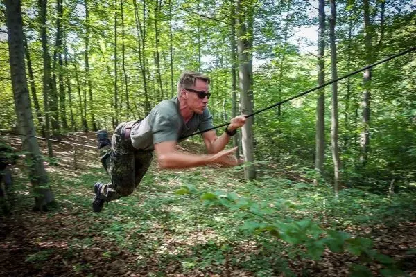 Mann überquert selbstgebaute Seilbrücke im Wald