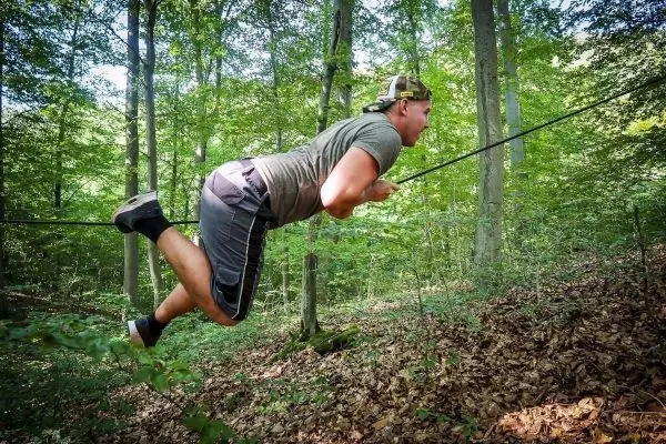 Mann überquert selbstgebaute Seilbrücke im Wald