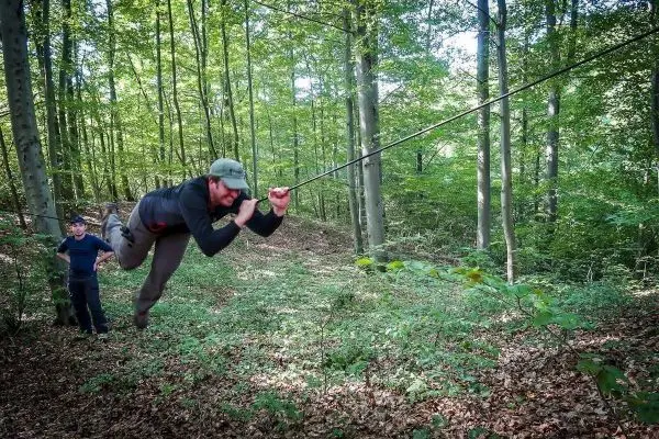 Mann überquert selbstgebaute Seilbrücke im Wald
