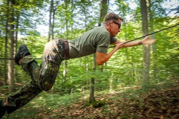 Mann überquert selbstgebaute Seilbrücke im Wald