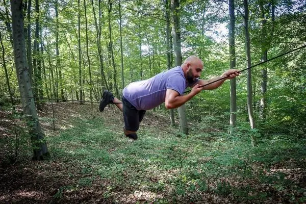 Person schwingt an einem Seil durch den Wald