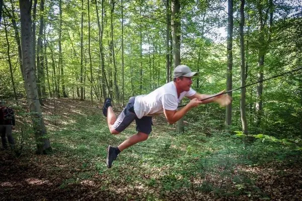 Person schwingt an einem Seil durch den Wald