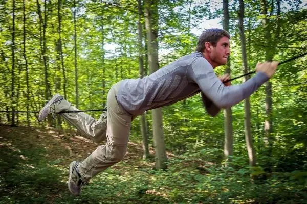 Person schwingt an einem Seil durch den Wald beim Survival Training