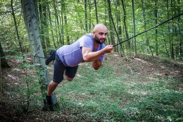 Person schwingt an einem Seil zwischen Bäumen