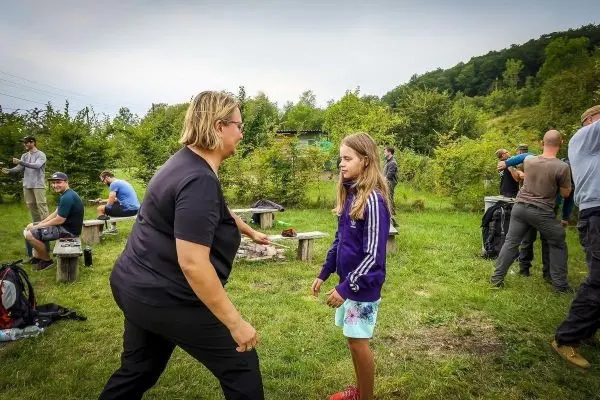 Person zeigt einem Kind eine Übung im Freien