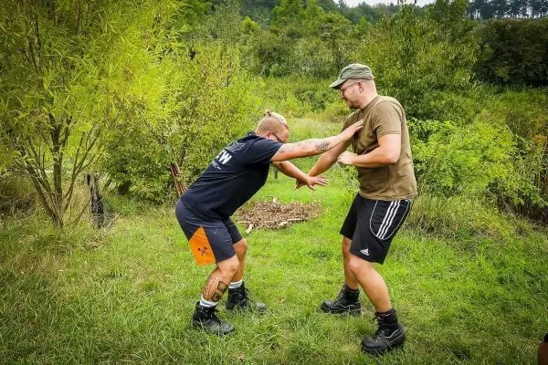 Zwei Personen üben eine Technik zur Selbstverteidigung im Freien