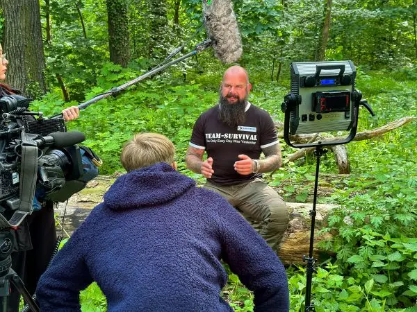 Interview in einem Wald mit Kamerateam und Mikrofon über einem Sprecher