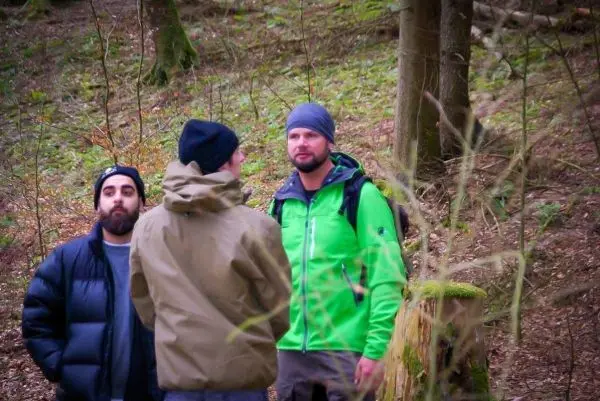 Drei Personen stehen im Wald und unterhalten sich