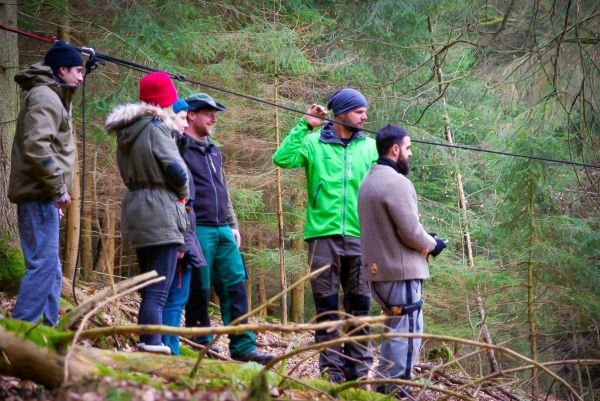 Gruppe beobachtet eine selbstgebaute Seilbrücke im Wald
