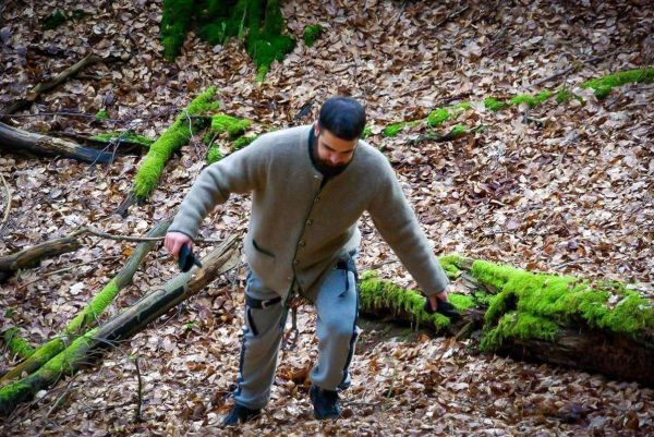 Mann klettert über einen umgestürzten Baum im Laubwald