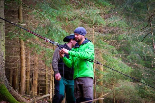 Zwei Personen arbeiten an einer selbstgebauten Seilquerung im Wald