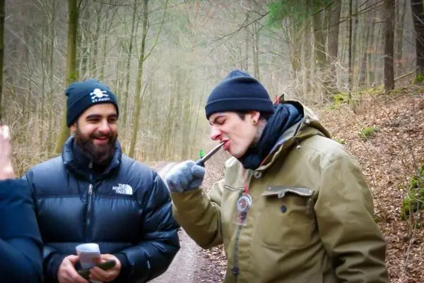 Zwei Personen stehen auf einem Waldweg, einer hält einen Becher in der Hand