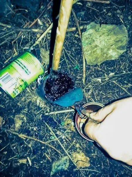 Ein improvisierter Kochtopf aus einem Behälter wird mit einer Holzstange gerührt