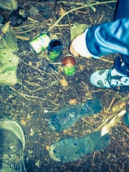 Kochgeschirr aus Dosen steht auf dem Boden, Hand greift nach einem Behälter