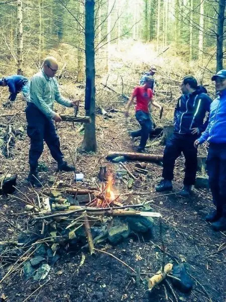 Mann hackt Holz für ein kleines Bodenfeuer in einem Waldgebiet