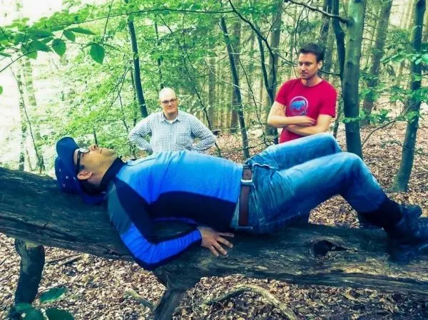 Mann liegt entspannt auf einem umgestürzten Baumstamm im Wald