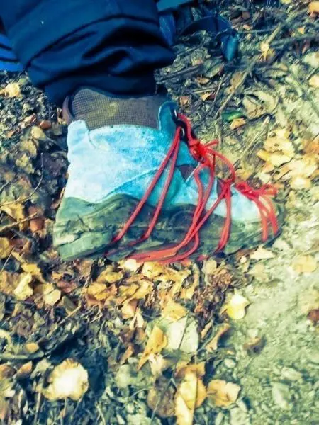 Wanderstiefel mit roten Schnürsenkeln auf einem Boden aus Laub